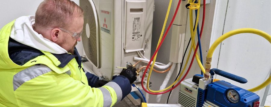 Opettaja Paavo Niemonen huoltamassa ilmalämpöpumppua.