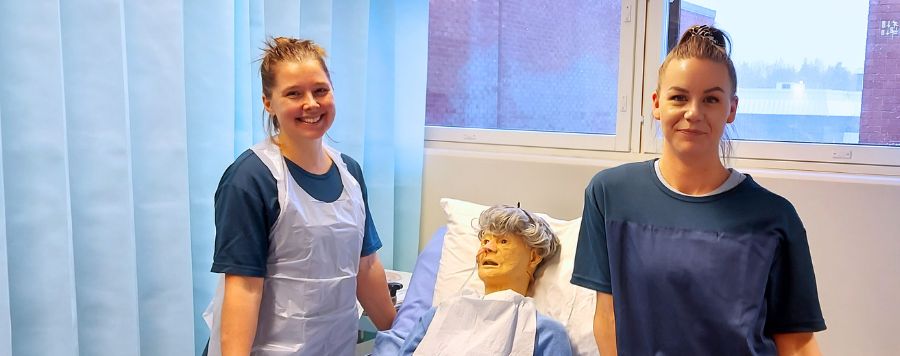Hoitoalan opiskelijoita potilasvuoteen ääressä.