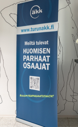Turun AKK:n tummansinipohjainen rollup, missä lukee "meiltä tulevat huomisen parhaat osaajat."