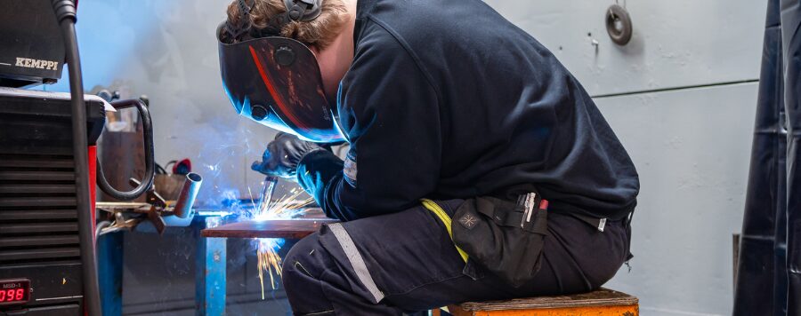 Henkilö hitsaa kappaletta.