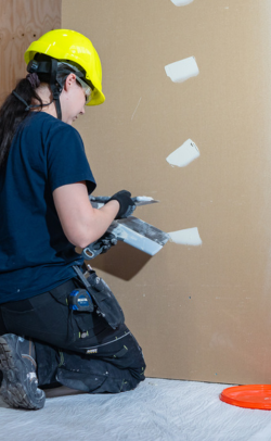 Opiskelija kittaa seiniä huoneistoremontoija-koulutuksessa.