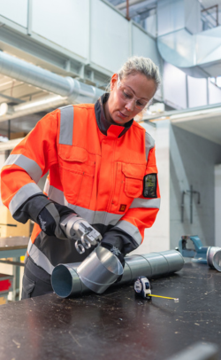 Opiskelija leikkaa ilmastointiputkea.