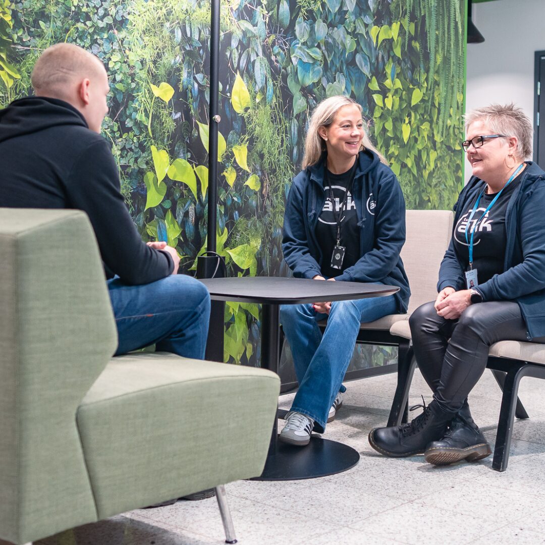 Henkilökunta juttelee opiskelijan kanssa pienen pöytäryhmän ääressä.