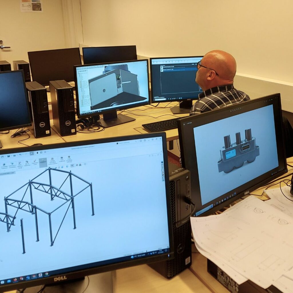 Kuva luokasta, jossa tietokoneiden näytöissä on auki ohjelmia, joita teknisen suunnittelun perustutkintokoulutuksessa käytetään.