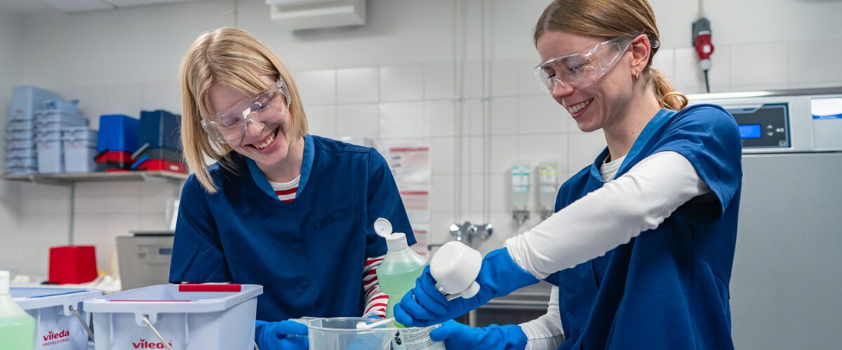 Kaksi puhtauspalvelualan opiskelijaa annostelee pesuaineita ämpäriin.